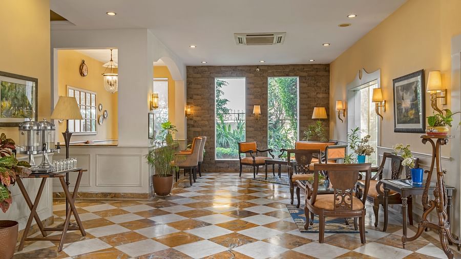 a view of the lobby with tables and chairs for sitting and large windows with views of greenery - The Manor, Kashipur