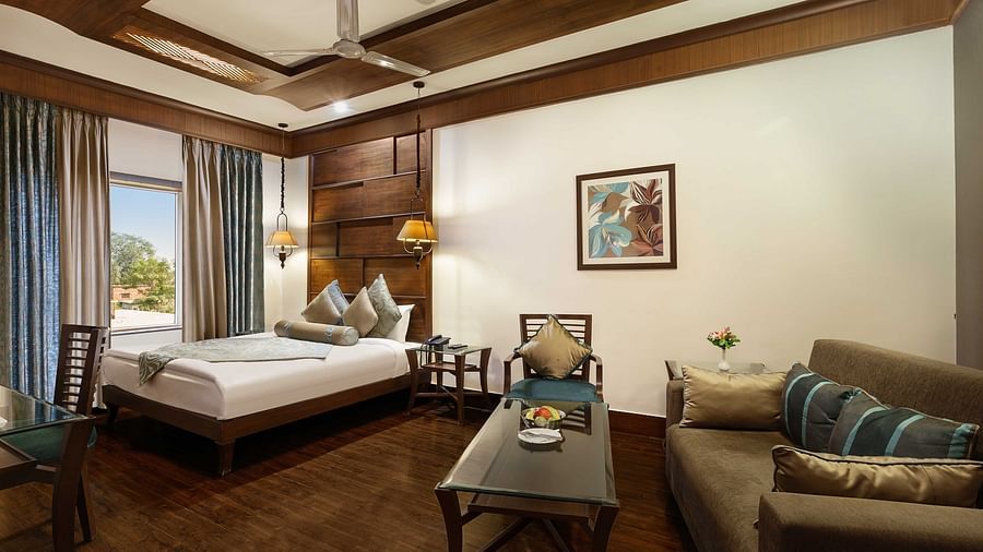 a view of a bedroom with a large bed in the corner and a sofa with a table - The Manor, Kashipur