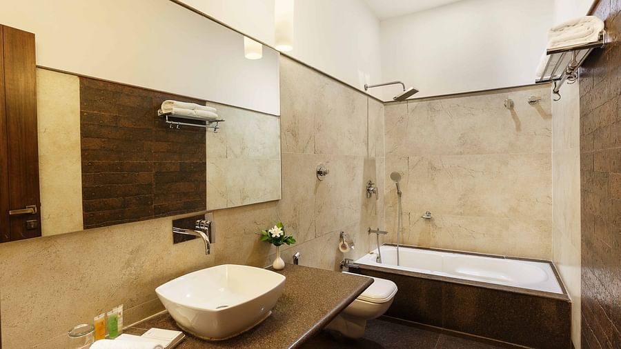 A modern bathroom featuring a granite countertop with a washbasin and a single elegant bathtub on one side