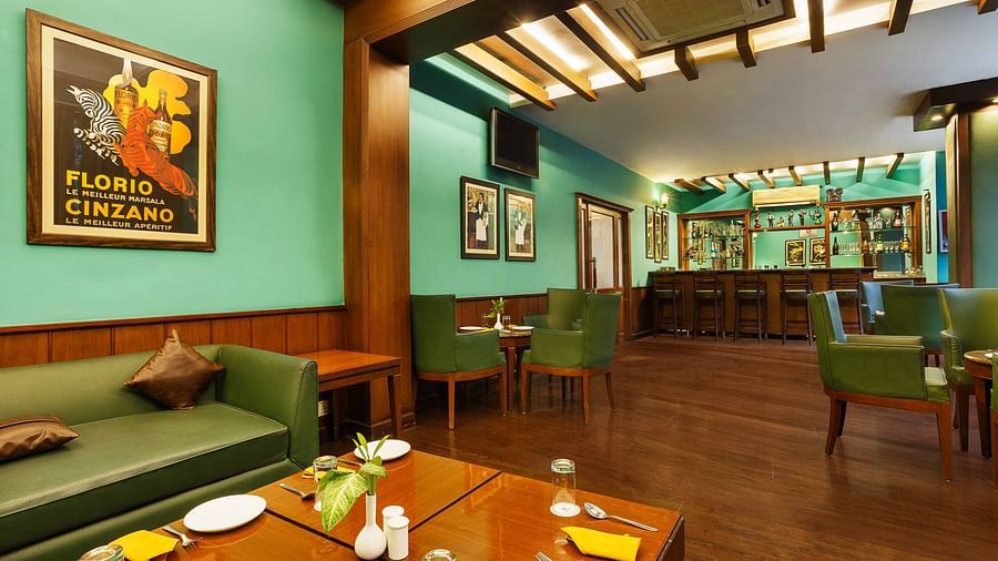 A sofa paired with a wooden table, elegantly set with plates and cutlery, alongside neatly arranged tables and chairs in a bar setup
