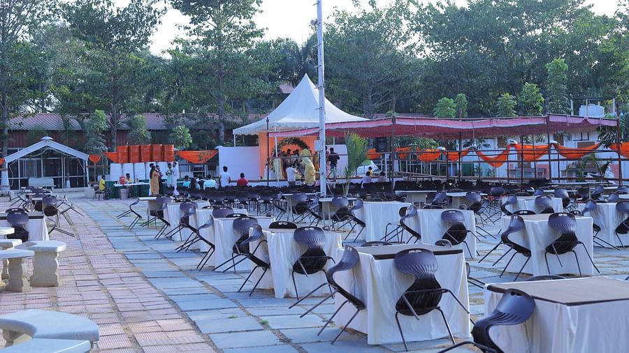 An open air setting of chairs around tables at The Meenakshi Resort by Welcome Inn Hospitality, Bangalore.