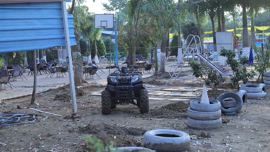 A muddy track lined by tired on both the sides with a truck car passing by at The Meenakshi Resort by Welcome Inn Hospitality, Bangalore.