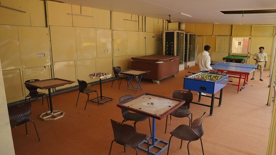 A game room with carrom boards placed on a table surrounded with chairs at The Meenakshi Resort by Welcome Inn Hospitality, Bangalore.
