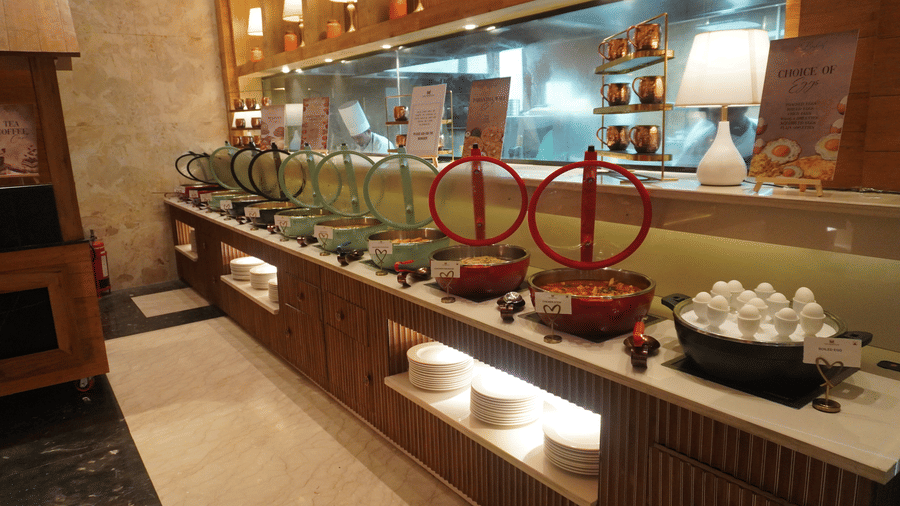 buffet station with various food dishes and serving equipment set up along a counter in a the Meriton..