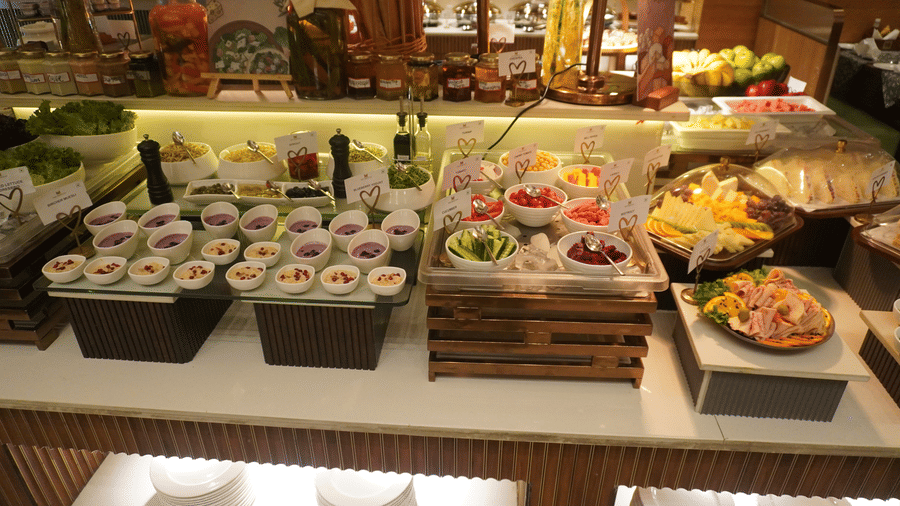 An indoor display of a buffet counter features various food items arranged in containers on a brightly lit wooden table at the Meriton. 