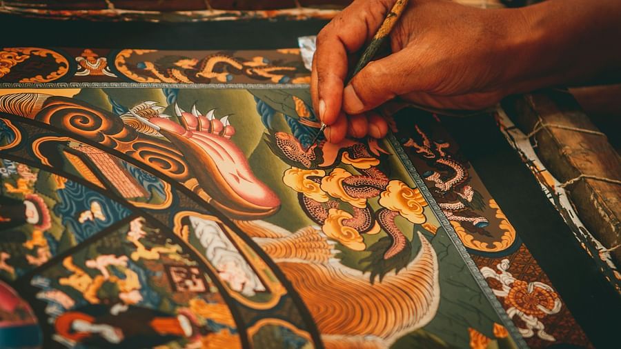 A close up shot of a person hand seen painting a Thangka painting