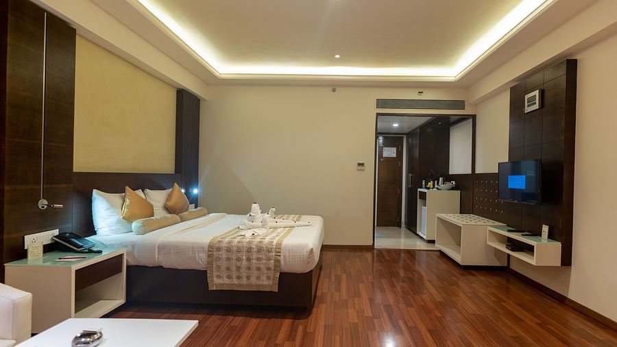 Luxury Room with king size bed, side table, sofa set and table at The President Hotel, Hubli