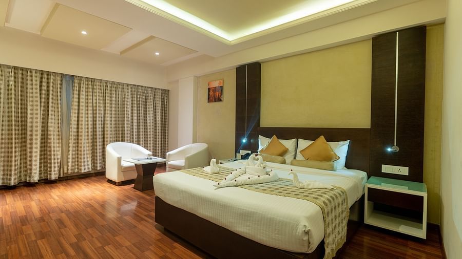 Luxury Room with king size bed, side table, sofa set and table at The President Hotel, Hubli