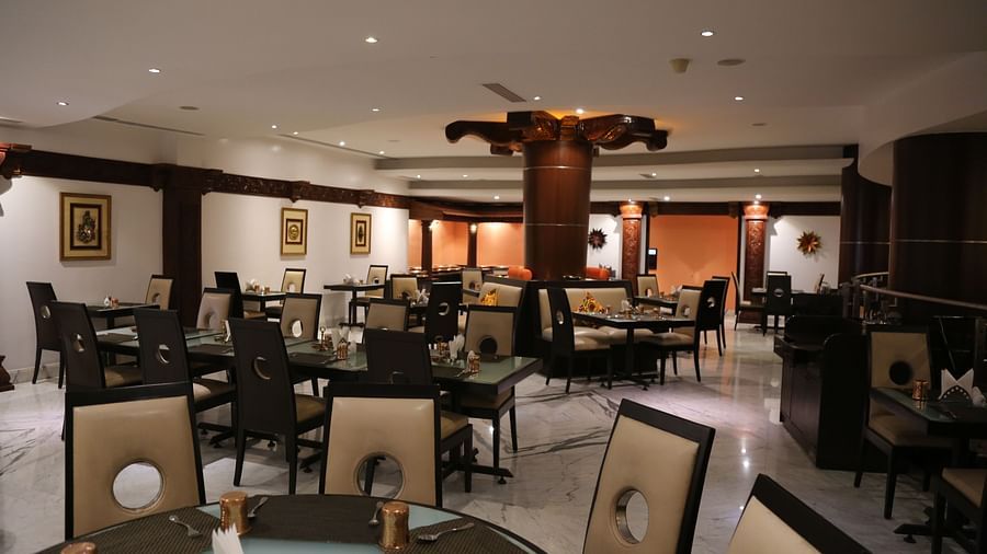 An elegant dining space with sophisticated black and white chairs, polished tables, and soft, ambient lighting at The President Hotel, Jayanagar.