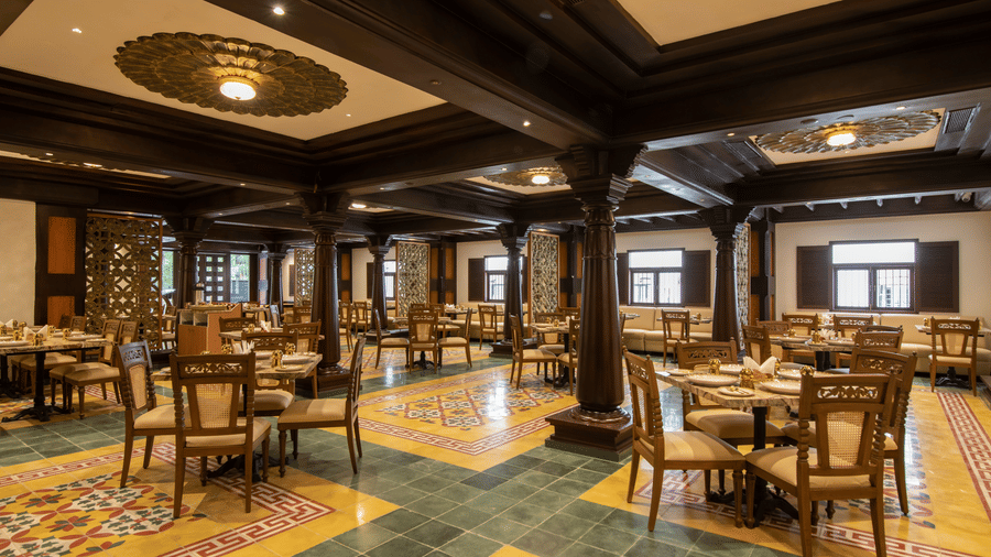 A traditional-themed dining room featuring wooden pillars, patterned floor, and seating arrangements - The President Hotel, Kumara Park, Bangalore