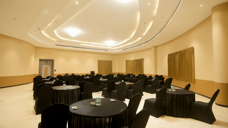 A photo of a hotel ballroom with several tables and chairs set up for an event | Conformance Hall