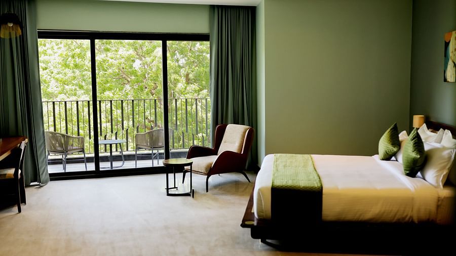 Club Suite with Valley View Sitout with a king size bed, a chair, and a balcony overlooking greenery.