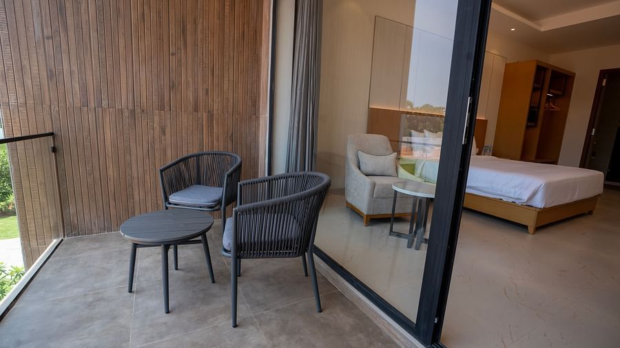 The balcony of the Pool View Bliss with two chairs and a round coffee table at The Shore, Trishvam.
