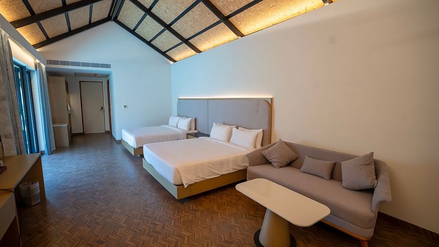 The bedroom of the Exotic Pool Villa with two double beds along with a grey coloured couch at The Shore, Trishvam.