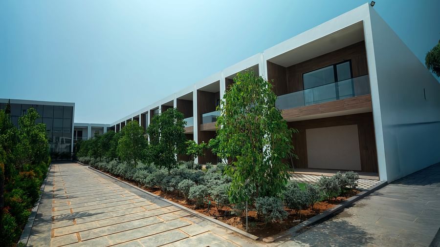 Corner view shot of a two storey building with tropical plants lined in front of it besides a pathway at The Shore Trishvam, Pondicherry.