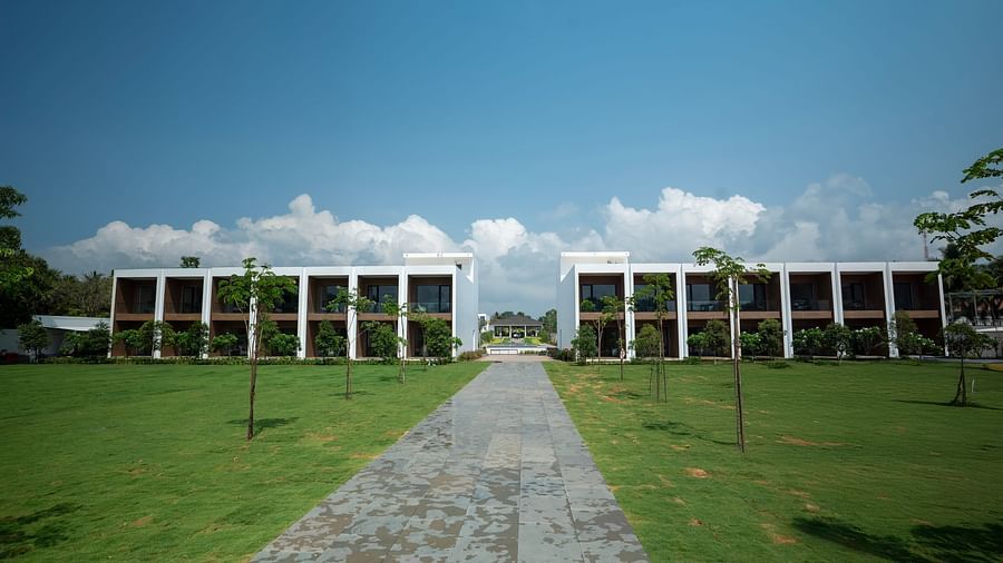  A lush green lawn at The Shore Trishvam, Pondicherry divided by a pathway in the middle with a clear blue sky in the background.