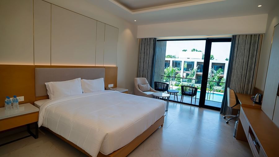 Full view shot of the Pool View Bliss room with tall french windows overlooking the swimming pool at The Shore, Trishvam.