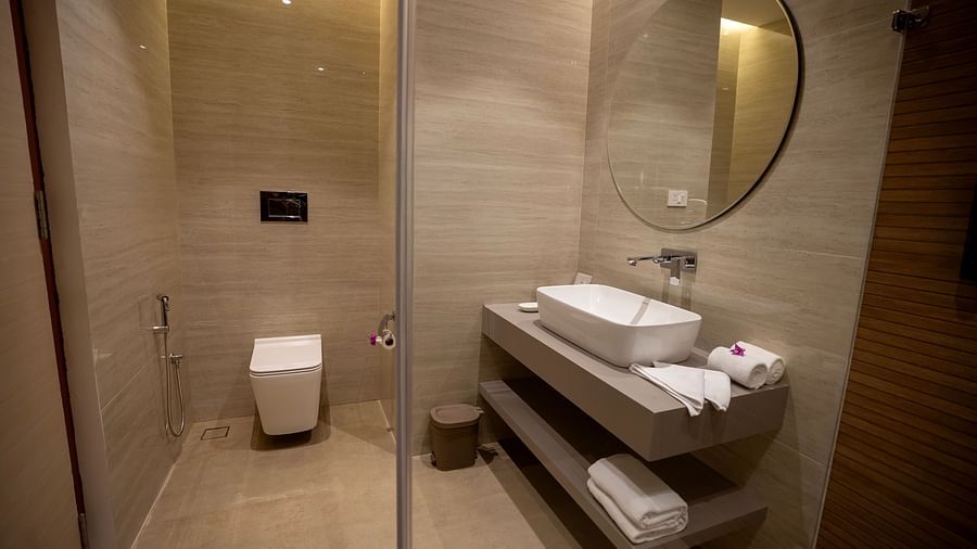 The bathroom of the Pool View Bliss featuring a commode and a vanity area with neatly rolled towels at The Shore, Trishvam.