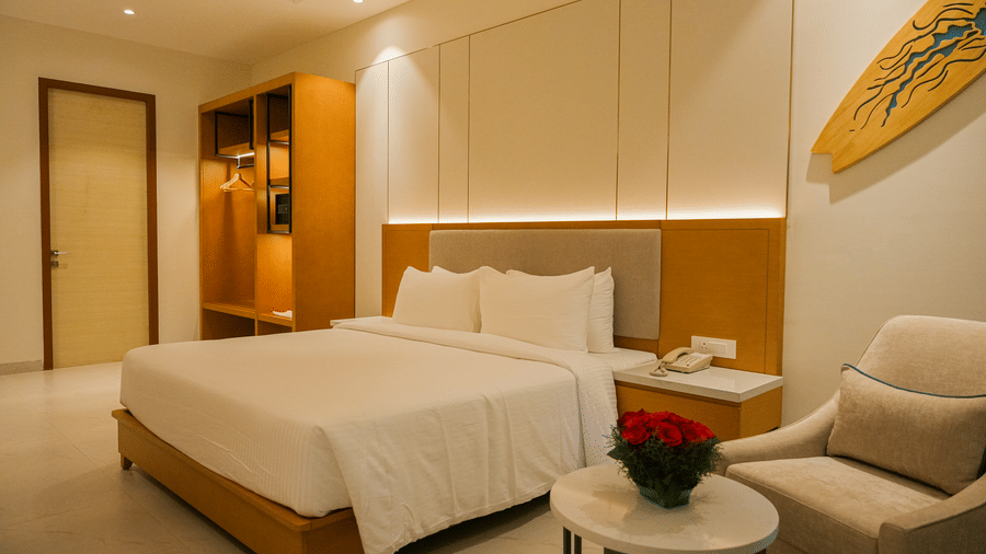 Elegant bedroom at The Shore Trishvam featuring a cosy king-size bed, warm wooden interiors, soft lighting, and modern amenities.