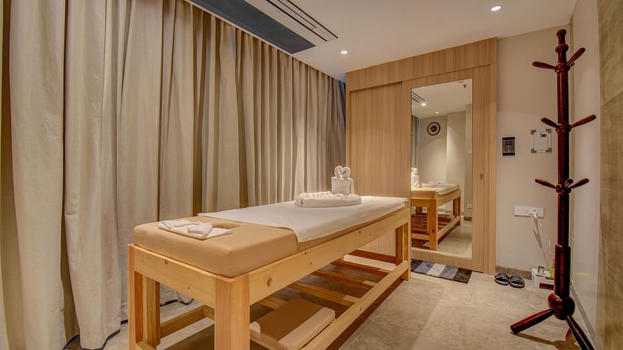A Spa bed at The SSK Solitaire Boutique Hotel & Spa, Gangapur Road - Nashik featuring a towel and mirror.