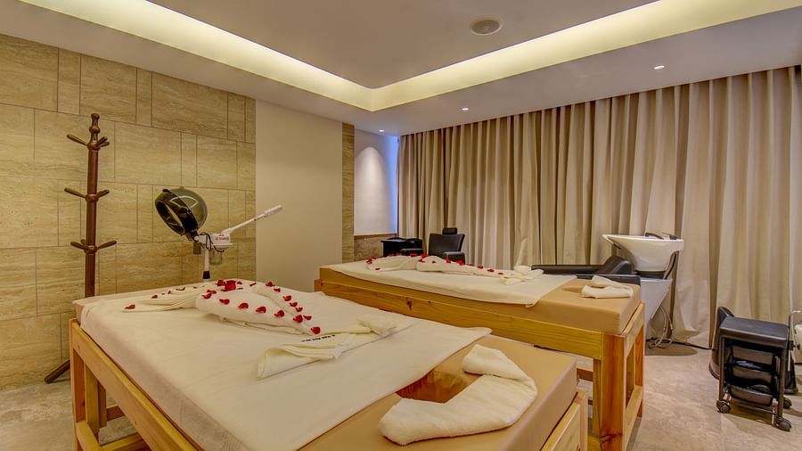 Two Spa bed at  The SSK Solitaire Boutique Hotel & Spa, Gangapur Road - Nashik featuring a towel in heart shape and flower petals.