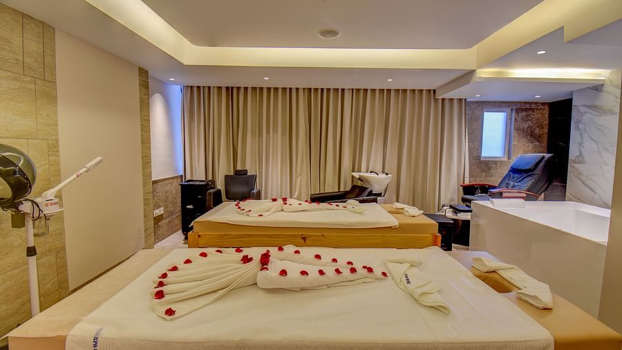 Side view of two Spa bed at The SSK Solitaire Boutique Hotel & Spa, Gangapur Road - Nashik featuring a towel in heart shape and flower petals.