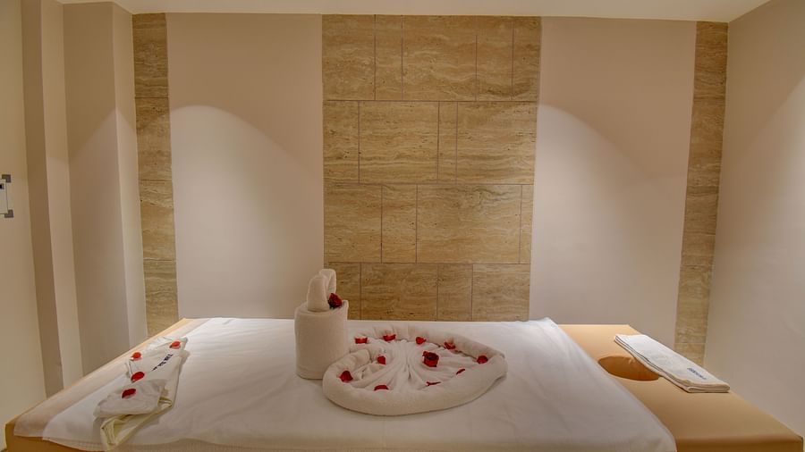 A Spa bed at  The SSK Solitaire Boutique Hotel & Spa, Gangapur Road - Nashik featuring a towel in heart shape and flower petals.