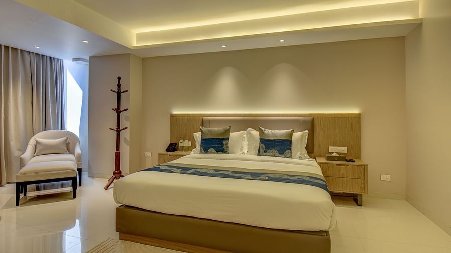 Close up of Deluxe King room at The SSK Solitaire Boutique Hotel & Spa, Gangapur Road - Nashik featuring a king size  bed, two armchairs, a small table, and a work desk with a chair.