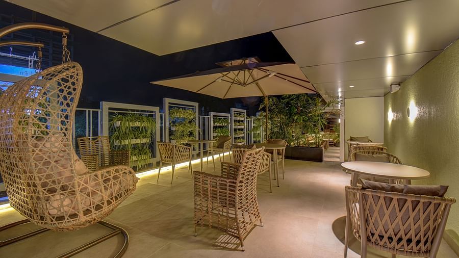 Seating area of a restaurant with table and chairs on a terrace with swing | The SSK Solitaire Boutique Hotel & Spa, Gangapur Road - Nashik