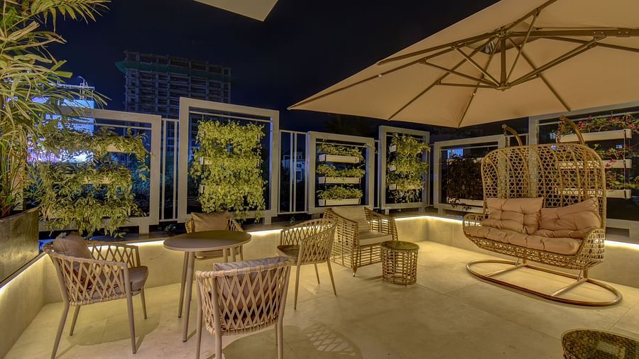 Side shot of seating area of a restaurant with table and chairs on a terrace with swing | The SSK Solitaire Boutique Hotel & Spa, Gangapur Road - Nashik