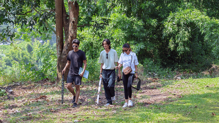 Three people hiking along a pathway surrounded by greenery at the Sylvan Retreat, Dehradun.