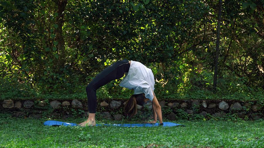 A woman practicing yoga surrounded by lush greenery at The Sylvan Retreat, Dehradun. 