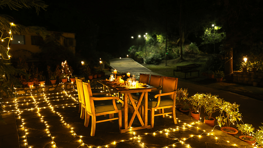 A lavish open-air dining setup with people enjoying a meal at night at The Sylvan Retreat, Dehradun.