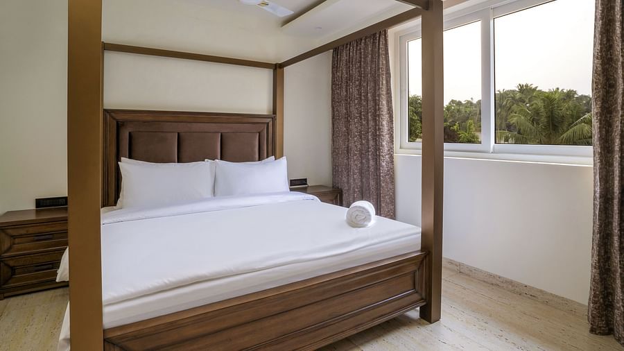 A double bed with wooden beams inside one of the rooms - The Tanisi Hotels & Resorts, Goa