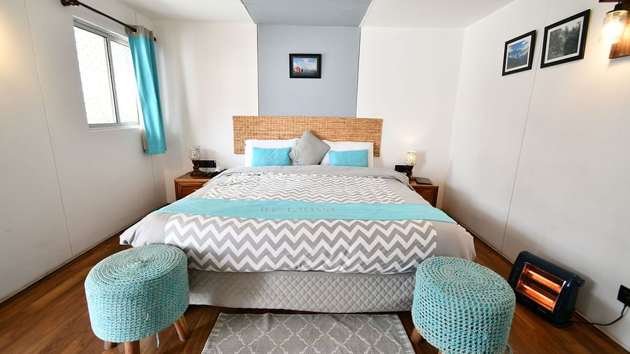 front view image of the comfortable bed with two cushioned stools in front of it - The Tattva Boutique Resort