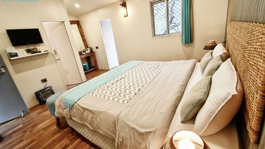 side view image of the deluxe room featuring a double bed and a wall mounted television in  front of it - The Tattva Boutique Resort