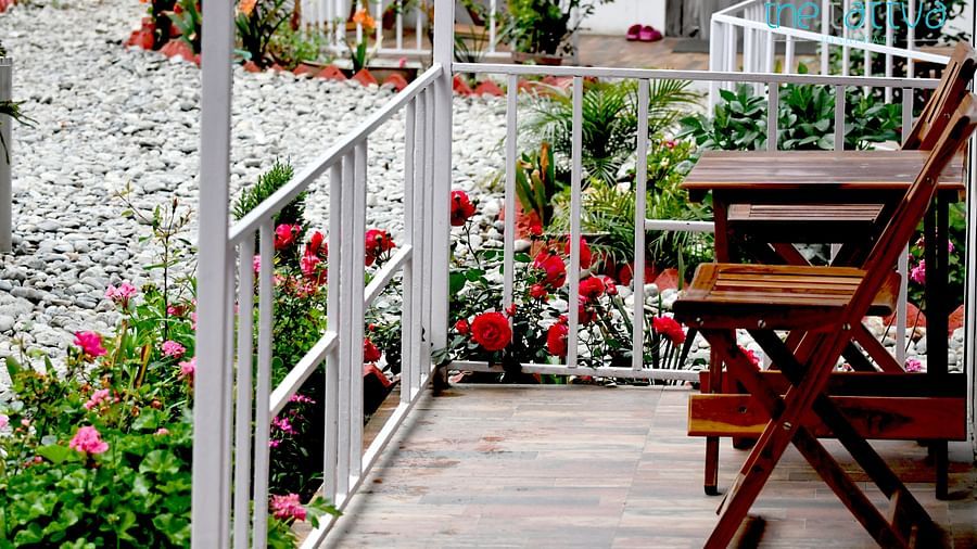 exterior image of the wooden porch at the deluxe room lined with beautiful floral bushes - The Tattva Boutique Resort