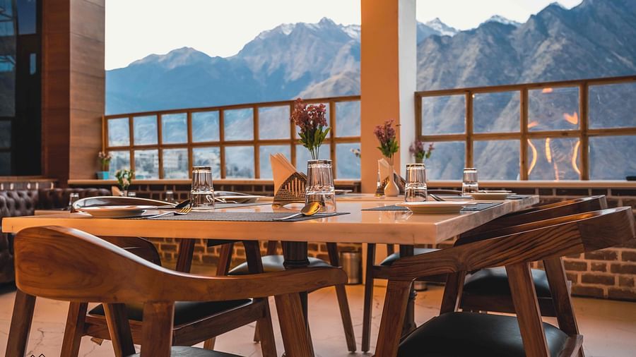 image of the indoor dining area of the alpenrose restaurant featuring a table over looking the beautiful mountain views - the tattva boutique resort
