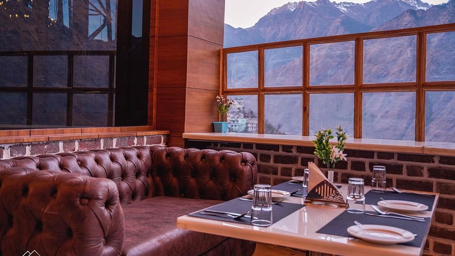 image of a maroon leather sofa with a dining table in front of it at the alpenrose restaurant - the tattva boutique resort