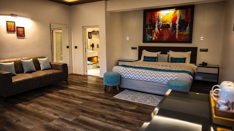 front view image of the bedroom at the pent house with a double bed and sofa in the corner of the room - The Tattva Boutique Resort