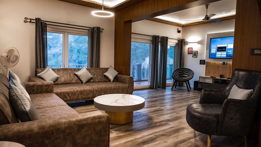 image of the living room of the pent house with a cushioned sofa and a round coffee table in front of it - The Tattva Boutique Resort