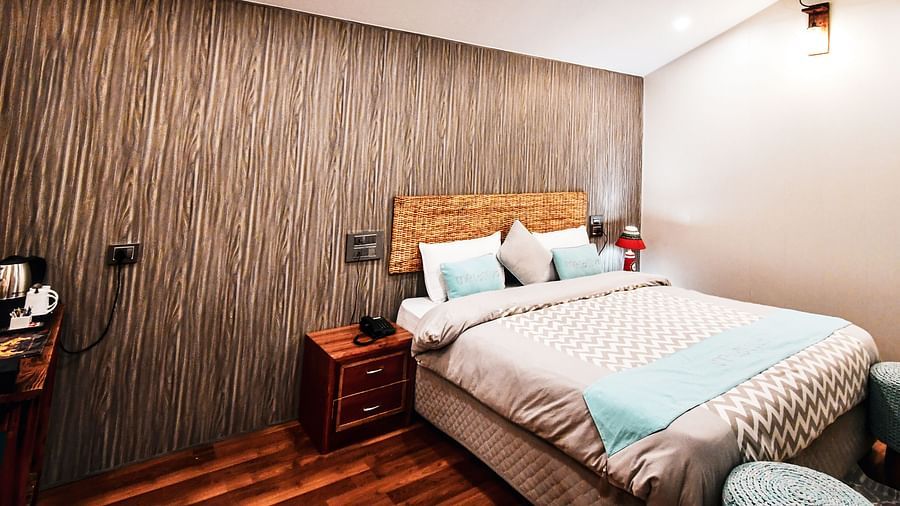 image of the standard room featuring a double bed in the corner with wooden flooring - The Tattva Boutique Resort