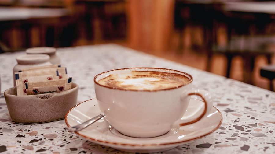 Image of a cup of coffee with sugar packets on the table | The Tattva Devprayag