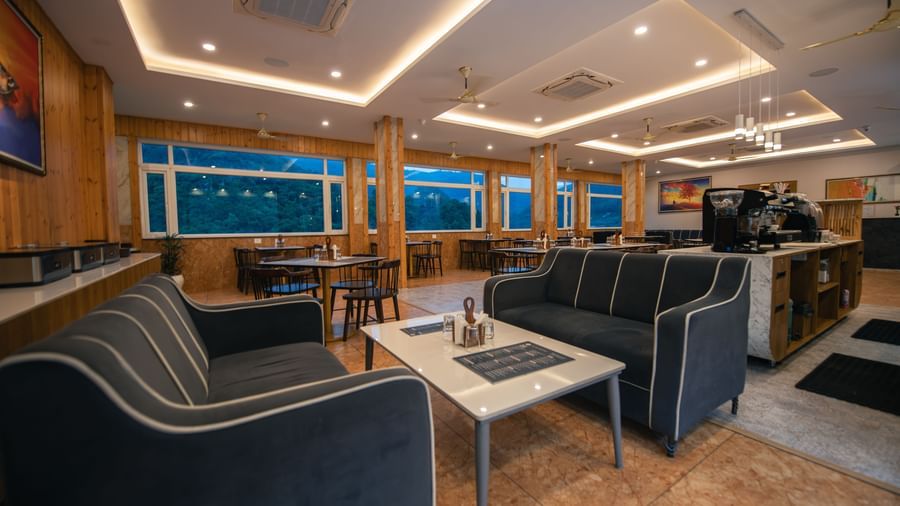 A restaurant at The Tattva Devaprayag with dark grey couches and a coffee table.