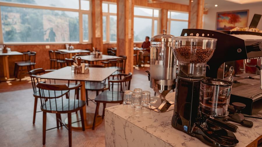 Image of the in-house restaurant featuring a fine dining setup, natural lights and a coffee machine | The Tattva Devprayag