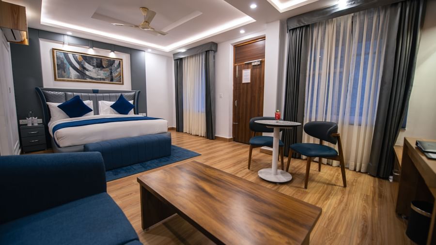 Bedroom at The Tattva Devaprayag with a bed dressed in blue blankets, a blue sofa, and a coffee table.