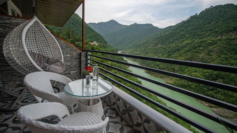 A balcony of a superior room at The Tattva Devaprayag offering a view of the expansive mountains and river. 