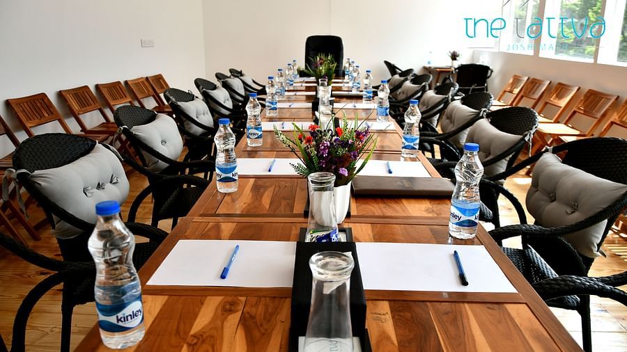 front view image of the conference hall featuring the expansive table decorated with flowers and stationery at the tattva, joshimath