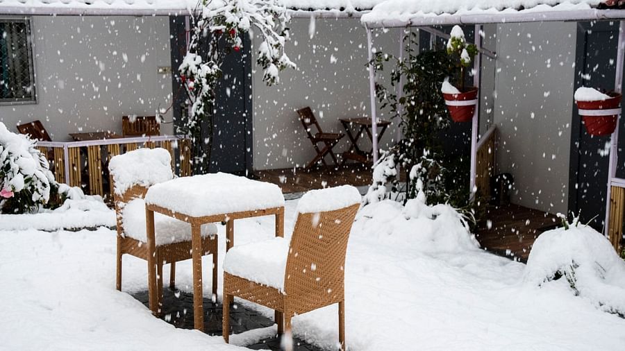 image featuring two chairs kept opposite to each other with table in between cover with snow at the tattva, joshimath
