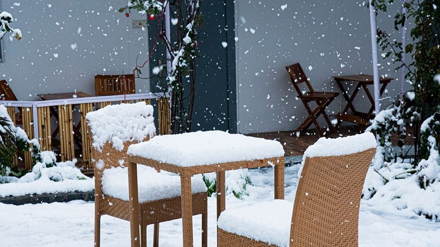 image featuring two chairs with a table in front of it cover with snow at the tattva, joshimath